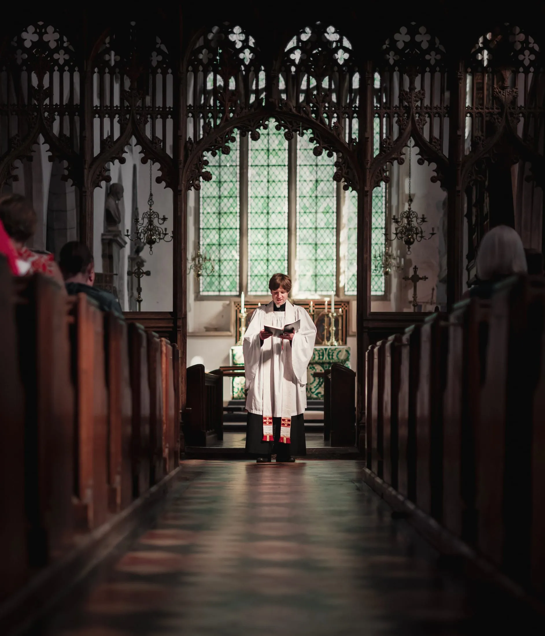 A robed minister at the altar of a candlelit church
